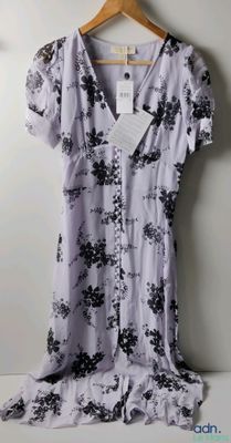 une robe à fleurs violette et noire suspendue à un cintre devant un mur blanc