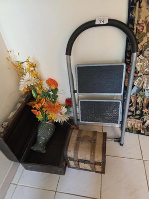 a metal step stool next to a vase of flowers on a tiled floor