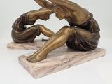 bronze statue of a woman sitting on a marble base with her hands in the air