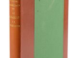 un vieux livre posé sur une table blanche, à côté d'un livre vert et marron