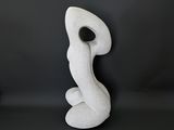 a white sculpture sitting on top of a table next to a black wall