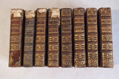 plusieurs vieux livres sont alignés sur une surface blanche