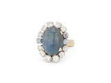 gros plan d'une bague avec une pierre bleue entourée de diamants blancs