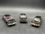 four toy cars are lined up in a row on a gray surface