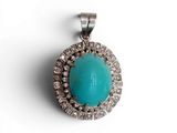 un gros plan d'un pendentif en turquoise et diamants sur fond blanc