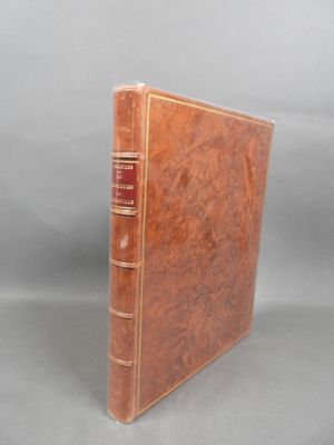 an old book with a brown cover sitting on top of a table