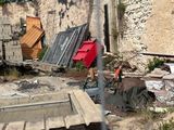un homme qui se tient devant un immeuble, un parapluie rouge à la main