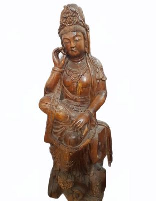 statue en bois représentant une femme assise sur un rocher, la main posée sur le menton
