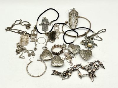 un tas de bijoux en argent posé sur une surface blanche