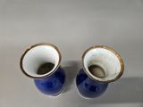 two blue vases with gold rims on a white surface