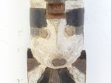 un masque en bois accroché à un mur blanc