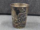 une coupe en argent ornée d'un oiseau, posée sur une table