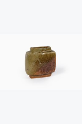 un petit vase vert posé sur une surface blanche