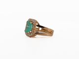 a close up of a gold ring with an emerald stone and diamonds