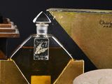 a bottle of perfume sitting next to a box of rocks