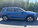 a blue mercedes suv parked in a parking lot with trees in the background