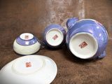 purple and white porcelain teapots and saucers on a brown surface