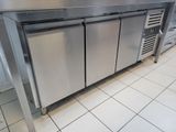 a stainless steel kitchen with three refrigerators on the counter