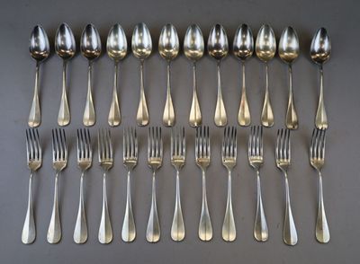 a lot of silver spoons and forks laid out on a table