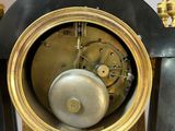 a black and gold clock that is on a stand