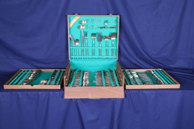 beaucoup d'argenterie dans un coffret posé sur une table bleue