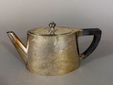 a silver tea pot with a wooden handle on a table