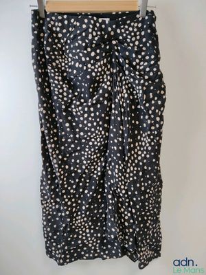 une jupe à pois noirs et blancs suspendue à un cintre