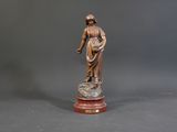 bronze statue of a woman holding a basket on a marble base