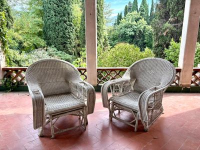 two wicker chairs sitting on the porch of a house
