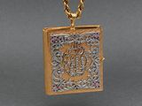a gold necklace with a picture of a book on it