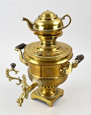 an antique brass coffee pot with a brass handle on a white background
