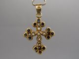 un gros plan d'un pendentif en forme de croix en or suspendu à une chaîne