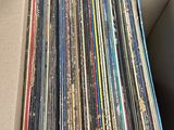 une boîte en carton ouverte remplie d'une multitude de disques vinyles de différentes couleurs