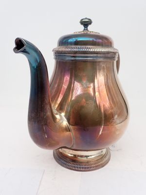 a silver teapot with a blue handle on a white table