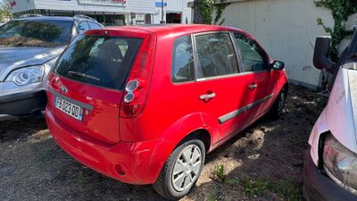 une petite voiture rouge garée sur un parking à côté d'autres voitures