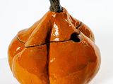 un petit objet en céramique en forme de citrouille posé sur une surface blanche
