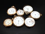 several different types of pocket watches sitting on a black surface