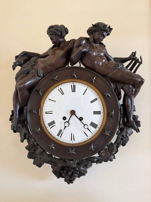 a clock that has a statue of two cherensils on it