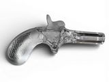 objet argenté en forme de pistolet posé sur une surface blanche, sur fond blanc