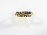 gros plan d'une bague en or avec des pierres bleues et blanches