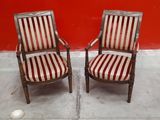 pair of antique chairs with striped upholstered seats in front of a red wall
