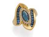 gros plan d'une bague en or avec des pierres bleues et blanches