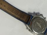 someone is holding a watch with a leather band on a white surface