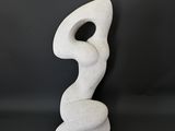 a white sculpture sitting on top of a table next to a black wall