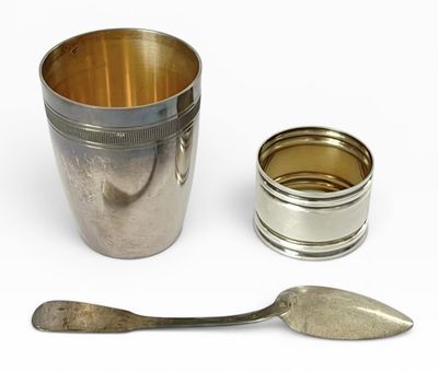 une tasse en argent avec une cuillère et un repose-cuillère à côté