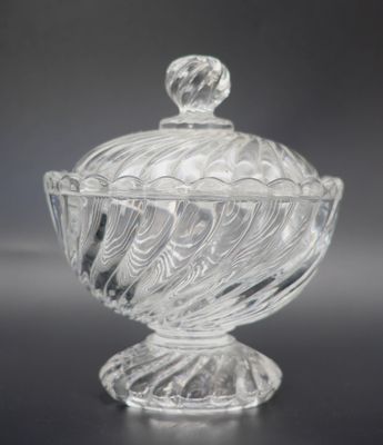 une photo d'un saladier en verre transparent muni d'un couvercle, posé sur une table