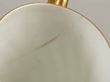 a close up of a white and gold vase on a table