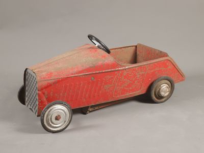 une petite voiture rouge posée sur une surface grise