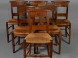 six chaises en bois sont alignées sur un fond gris