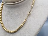 a gold beaded necklace on a mannequin mannequin